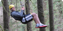 Participant ziplines after a successful ropes course team building activity in Portland Oregon
