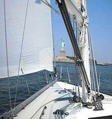 The Statue of Liberty peeks through the sails during our sailing team building activity in Jersey City New Jersey