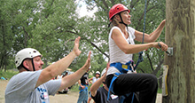 Participant begins ascent while spotters provide support during our ropes course team building activity in North Dakota
