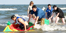 Boat glides to shore with the help of teammates after surviving the waves during our Build a Boat team building activity in Galveston Texas