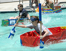 Participant hastily paddles to win the race during our Build a Boat team building activity in Houston Texas