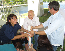 Team strategizes on how to keep dry during the Leaky Pipe team building activity in Woodlands Texas